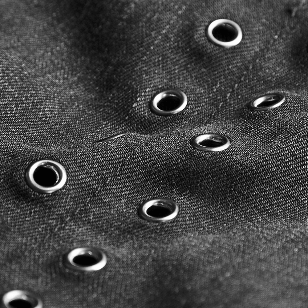 Close-up of black denim fabric featuring metallic eyelets for a punk-inspired style.