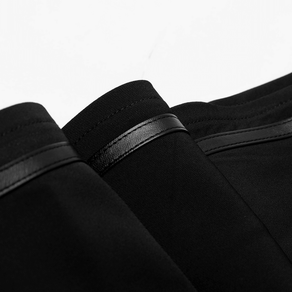 Close-up of black high-waisted skirt detailing with pleats and decorative buckle accents.