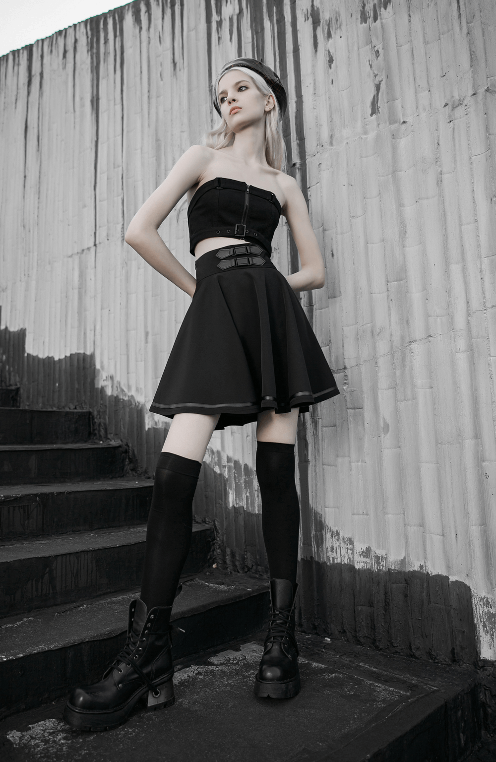 Punk Rave black high-waisted mini skirt with buckle, styled edgy with crop top and thigh-high socks.