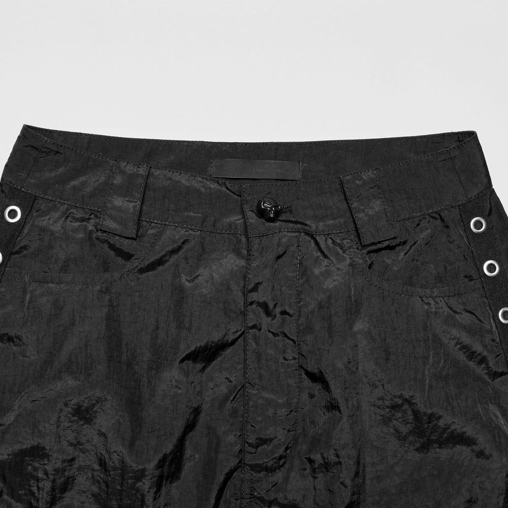 Close-up of the waistband of black cargo pants with eyelet webbing and button detail, showcasing urban streetwear style.