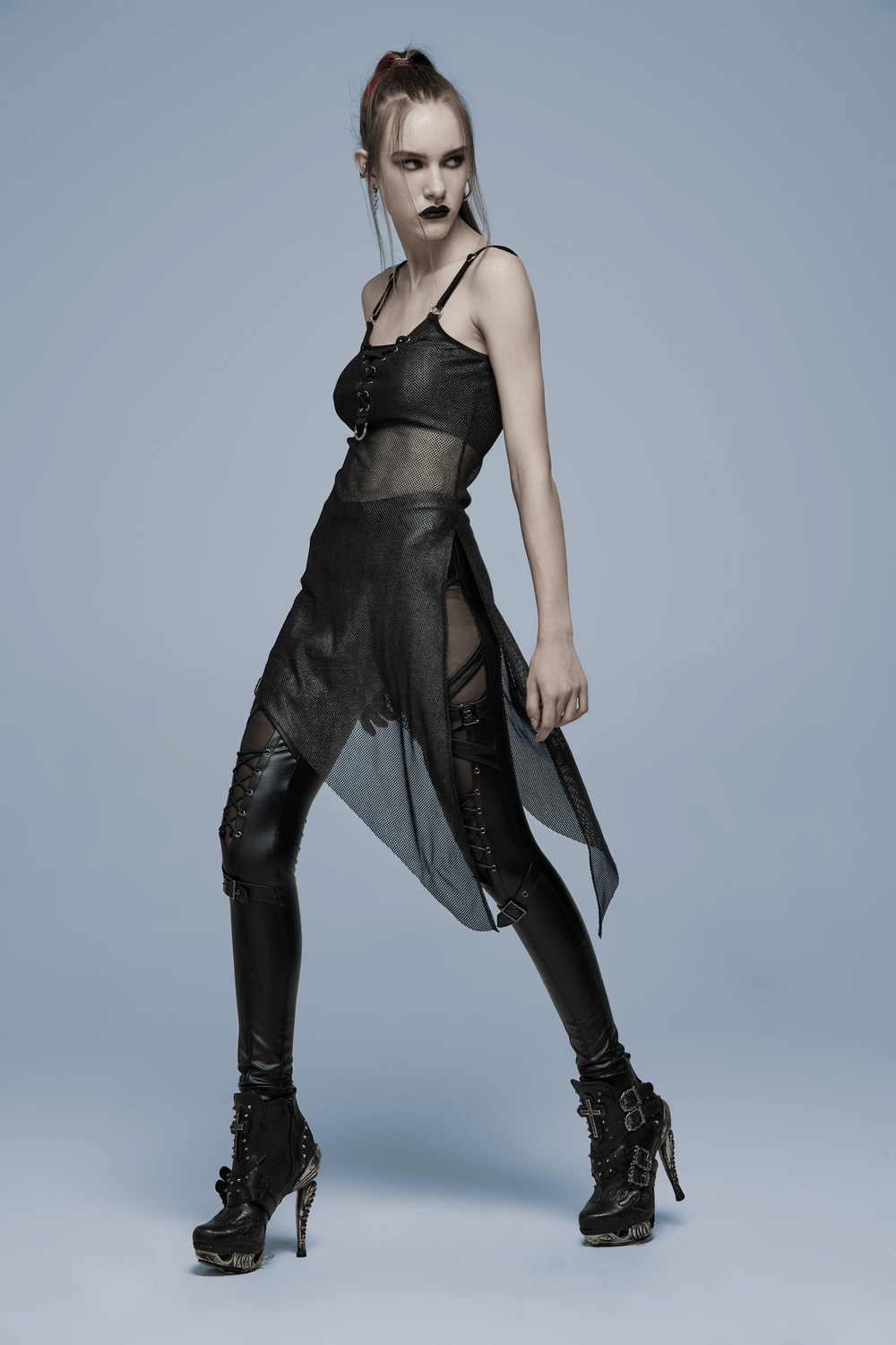 Edgy model in mesh and faux leather outfit featuring Goth aesthetic and high-heeled boots, showcasing punk style.