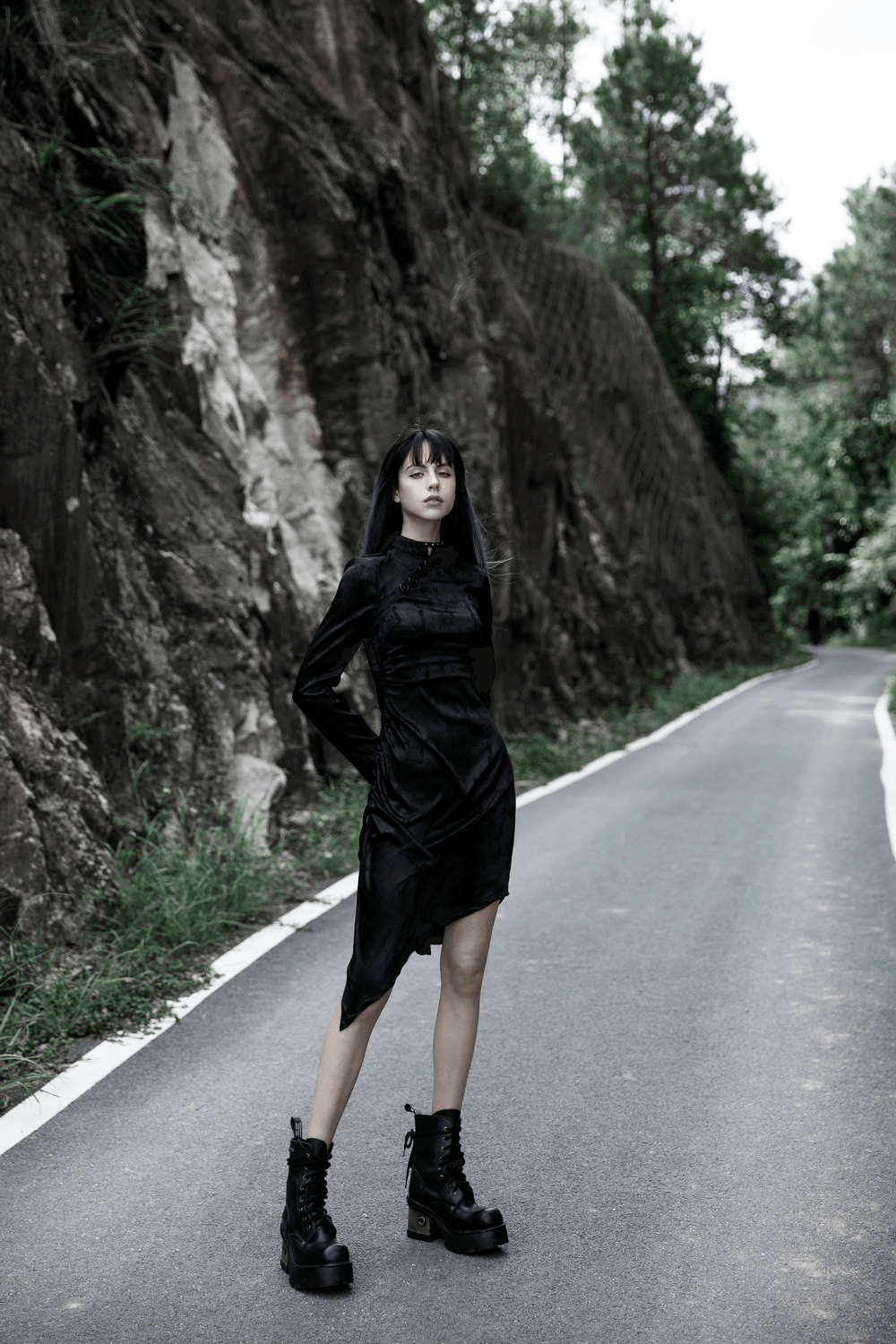Gothic cheongsam dress with pointed hem modeled on a road surrounded by rocky terrain.