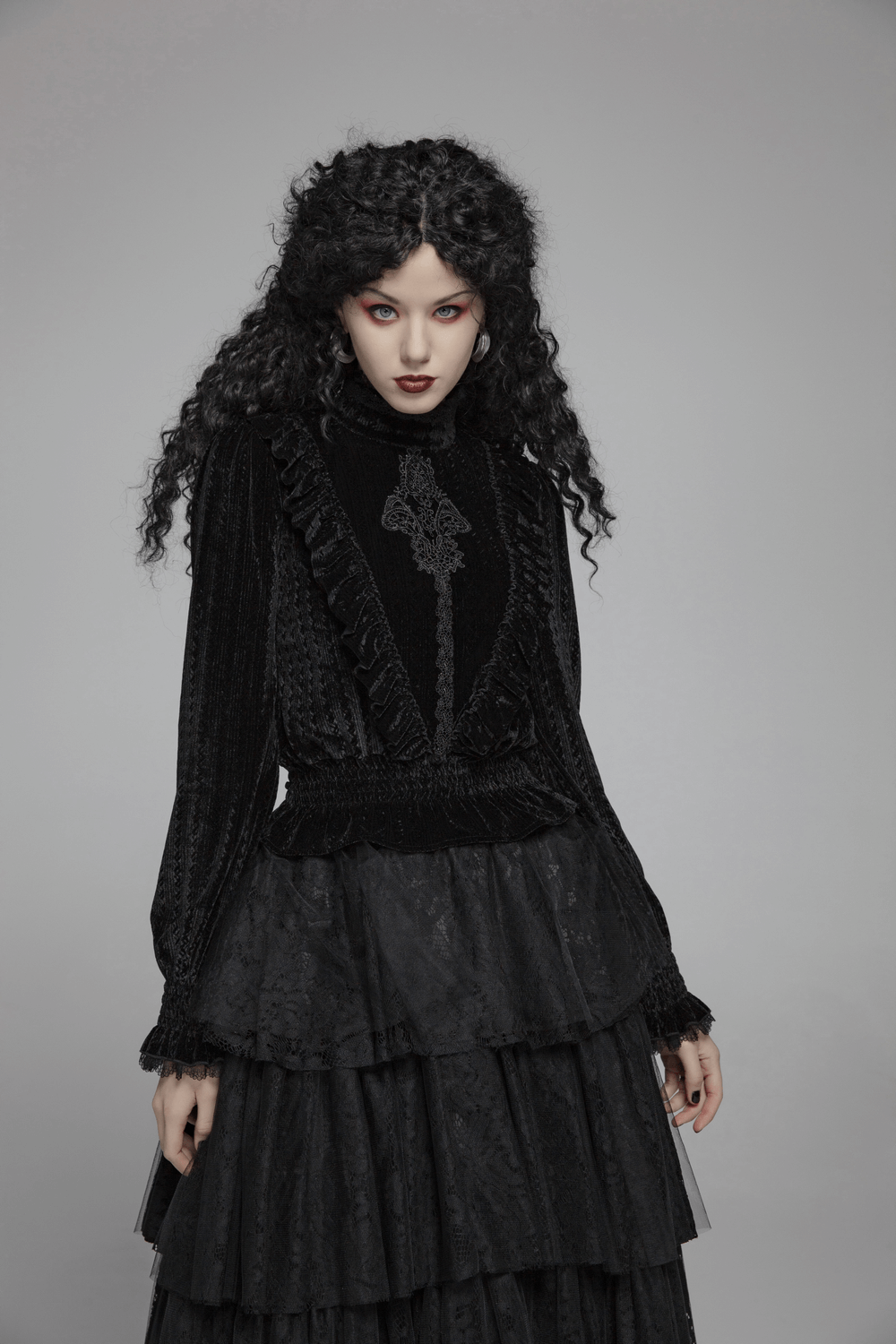 Gothic model wearing a dark velvet blouse with ruffle collar, long sleeves, and layered skirt, exuding Victorian elegance.