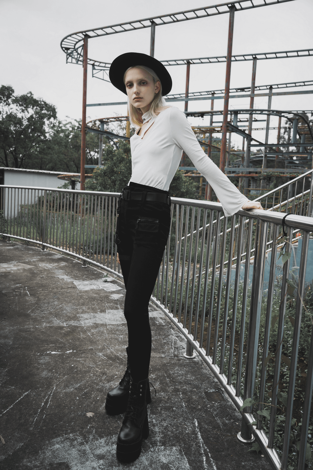 Model in white top and black mid-rise jeans with detachable belt, showcasing edgy punk rock style.