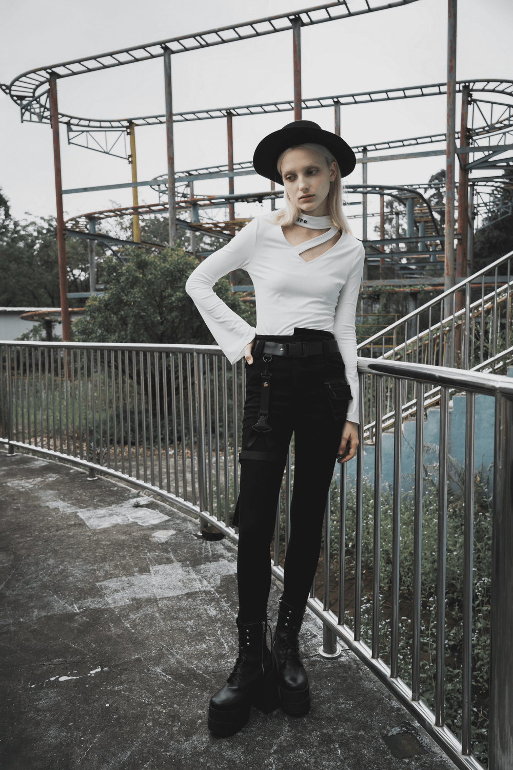 Punk Rave model wearing detachable belt mid-rise slim denim jeans and edgy top at an abandoned amusement park.