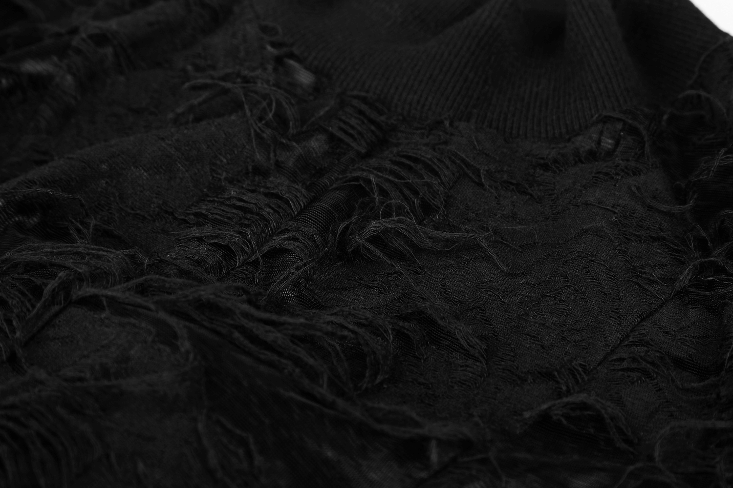 Close-up of black lace fabric showcasing Gothic style with intricate frayed detailing and texture.
