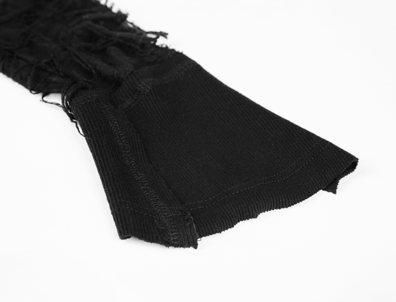 Black corduroy fabric close-up with fringed detailing and hem, showcasing texture for fashion design.