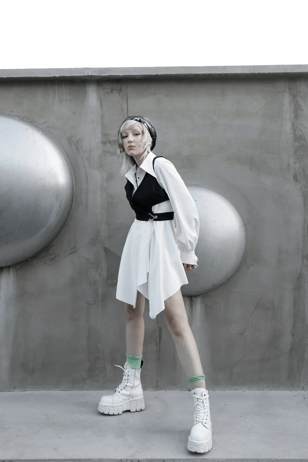 Model showcasing Punk Rave Gothic white swallowtail shirt dress with asymmetrical hem and chunky boots, against a modern backdrop.
