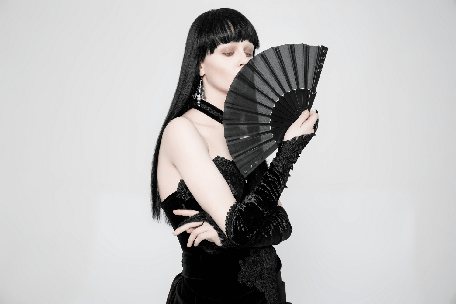 Model elegantly holding a Gothic spiked hand fan, showcasing dark romance and edgy elegance in fashion.