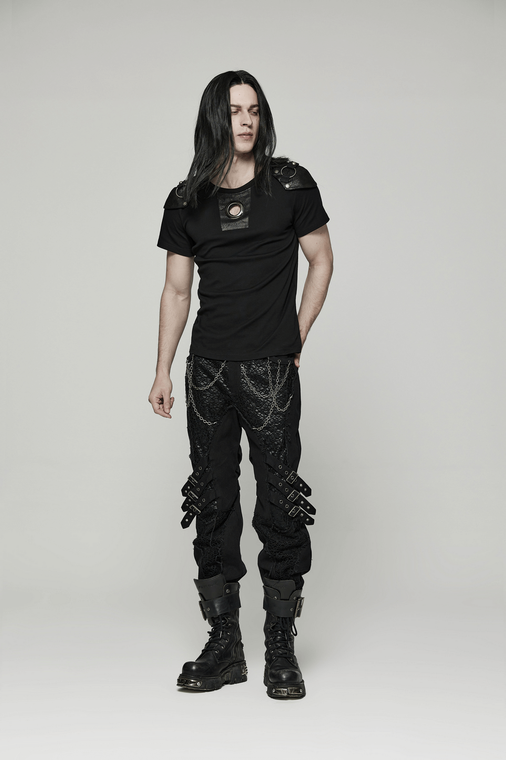 Male model in punk rivet armor t-shirt with detachable panel and edgy black pants, exuding rebellious style.