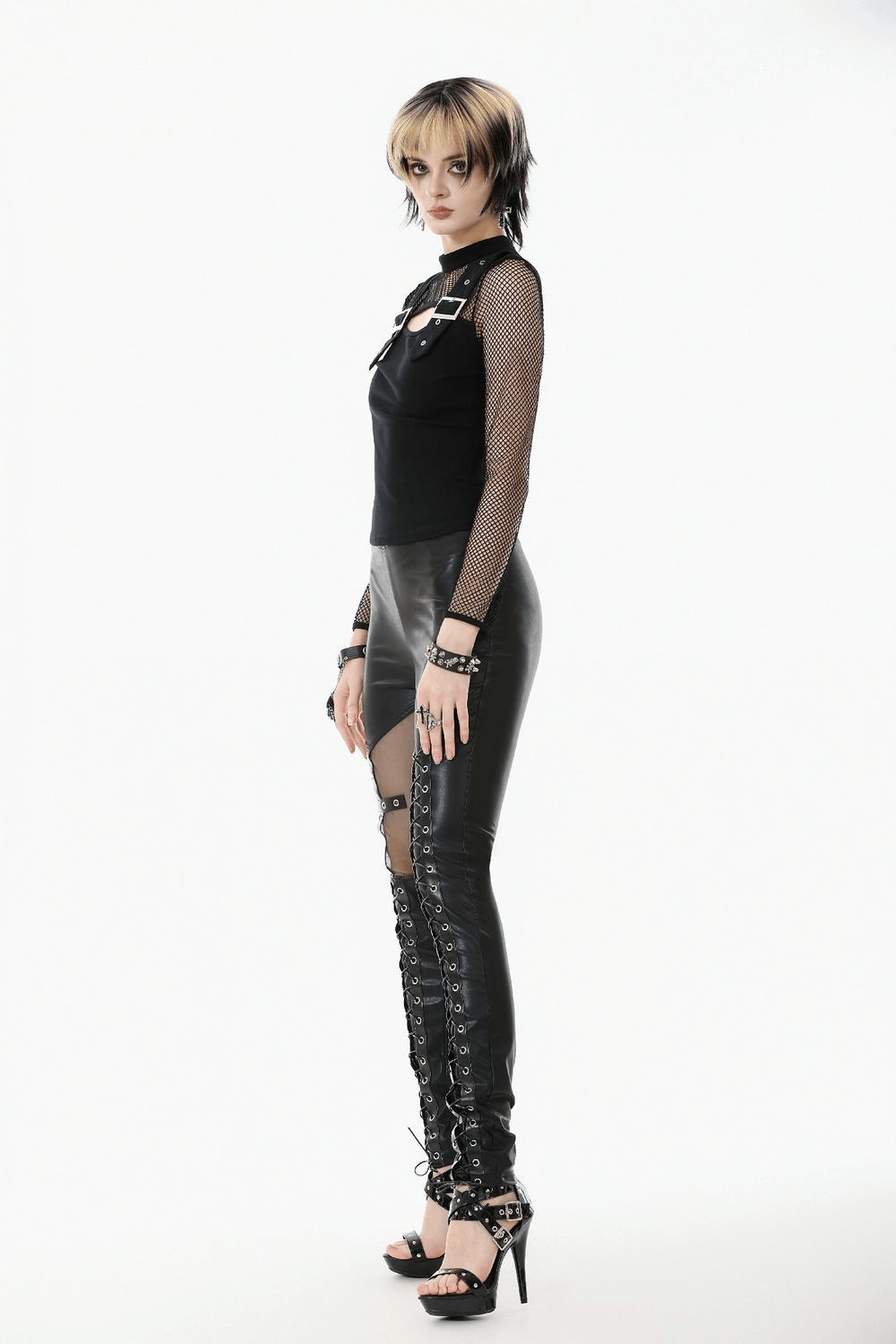 Punk Rock Black Fishnet Sleeved Top with Cutout and Straps paired with edgy leather pants and stylish heels.