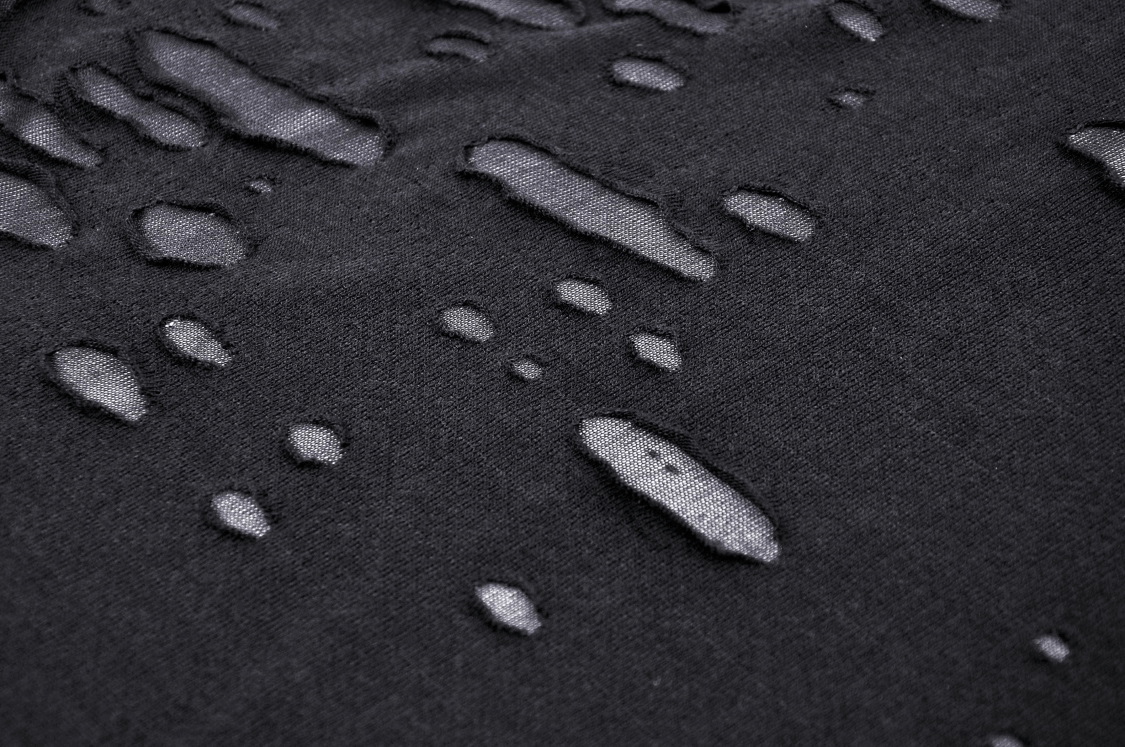 Close-up of textured black fabric with unique water droplet patterns for punk rock style.