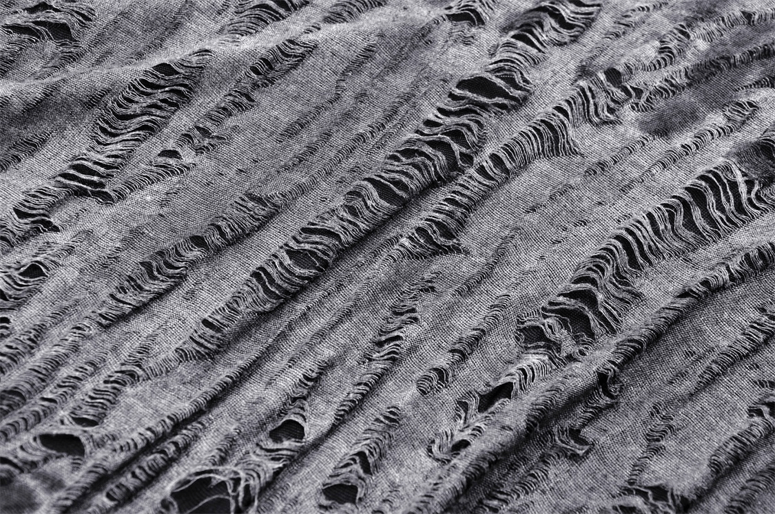 Close-up of edgy ripped fabric showcasing punk rock style; perfect for a rebellious off-shoulder hoodie.