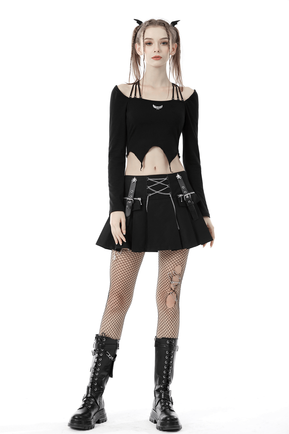 Punk rock fashion: model in black pleated mini skirt with chains, edgy crop top, and fishnet stockings.