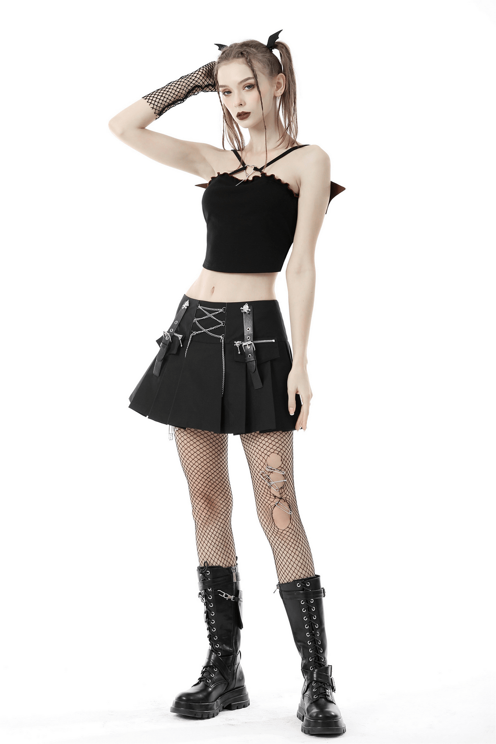 Model wearing a punk rock pleated mini skirt with chain details, paired with a black top and fishnet stockings, showcasing edgy style.