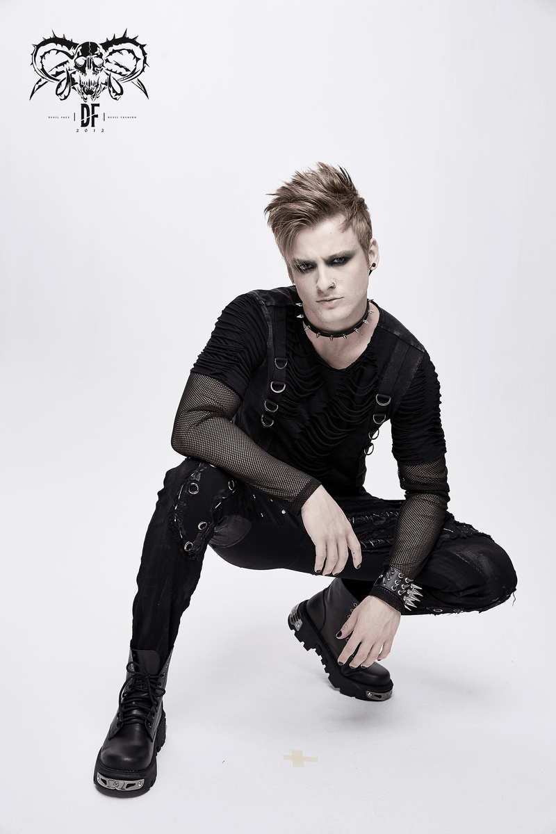 Stylish male model in punk rock attire featuring black pants with studs and layered top, exuding edgy fashion vibes.