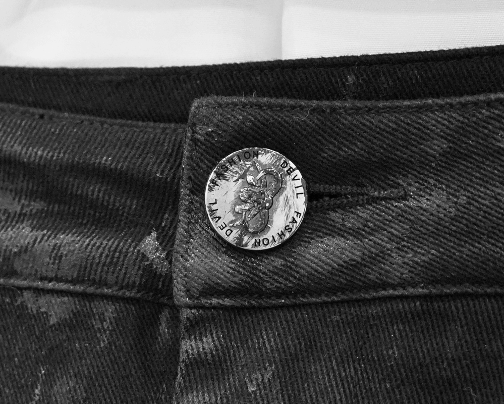 Close-up of a black trouser button featuring punk rock design, perfect for style enthusiasts.