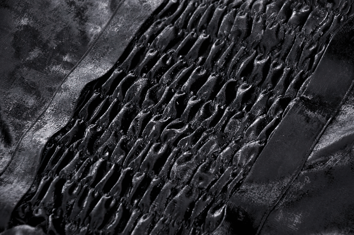 Close-up of smocked black velvet fabric, showcasing intricate ruffles and layered texture for a gothic look.