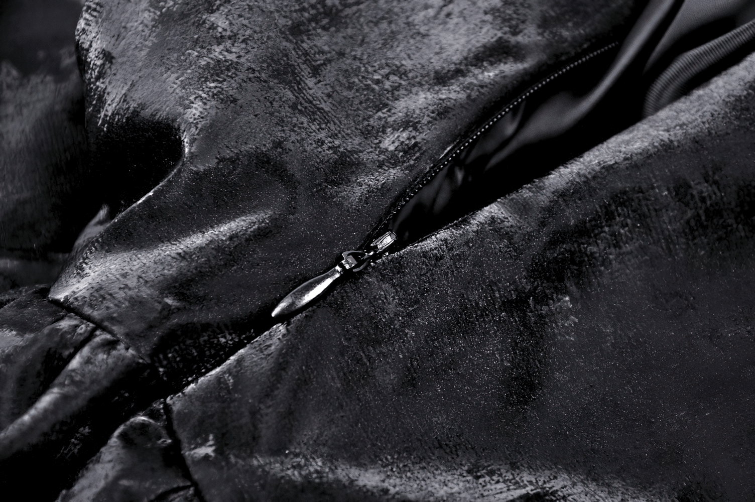 Close-up of shiny black PU leather fabric and zipper detail on a punk layered mini dress.