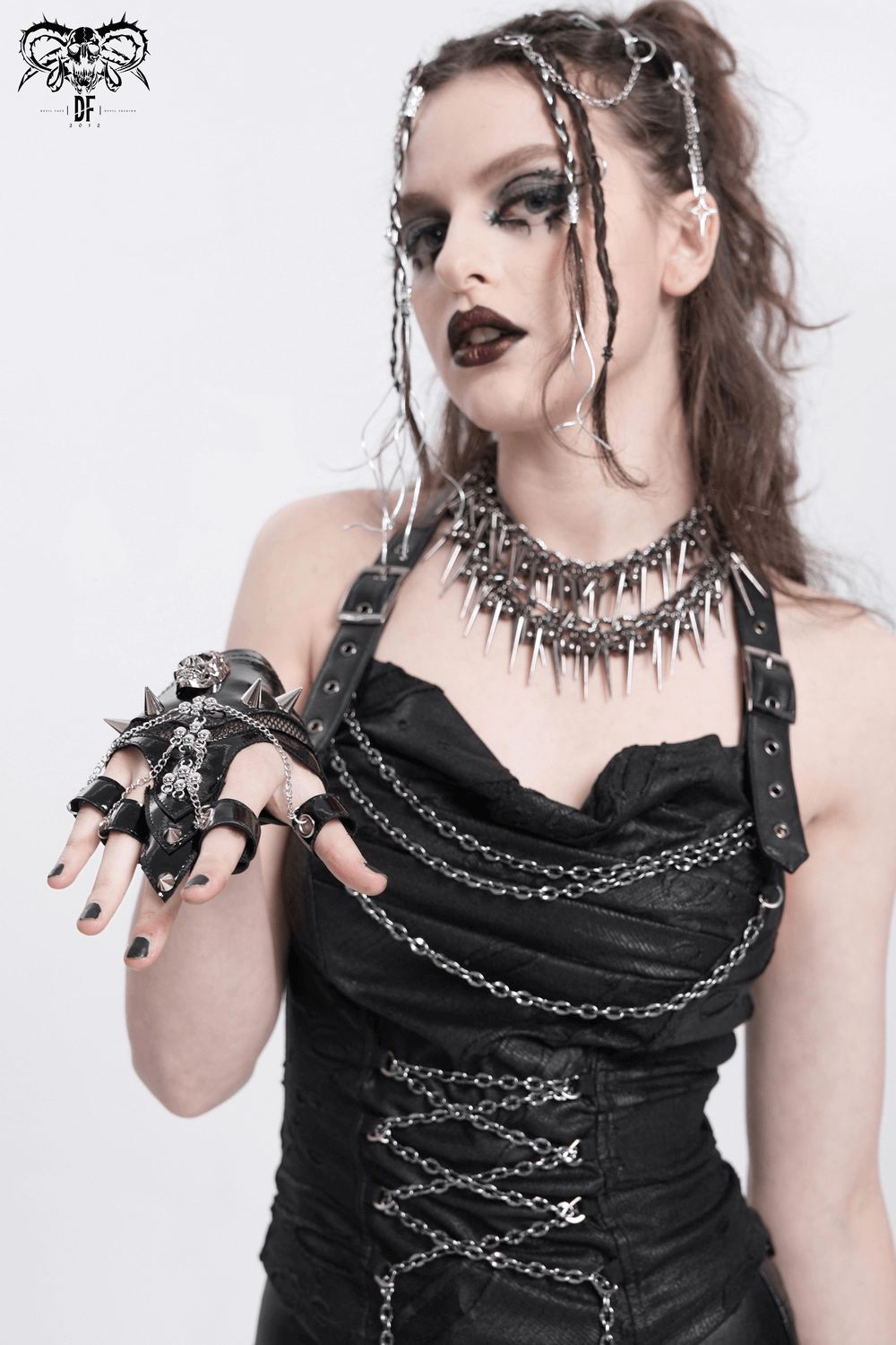 Model wearing punk skull studded half-finger gloves with chains and spiked accessories, showcasing gothic fashion chic.