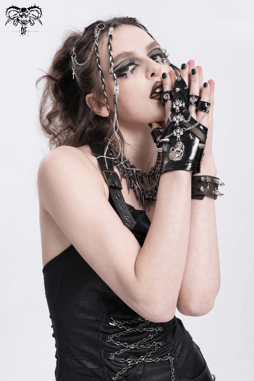 Gothic model showcasing punk skull studded half-finger gloves with chains, embodying edgy fashion.