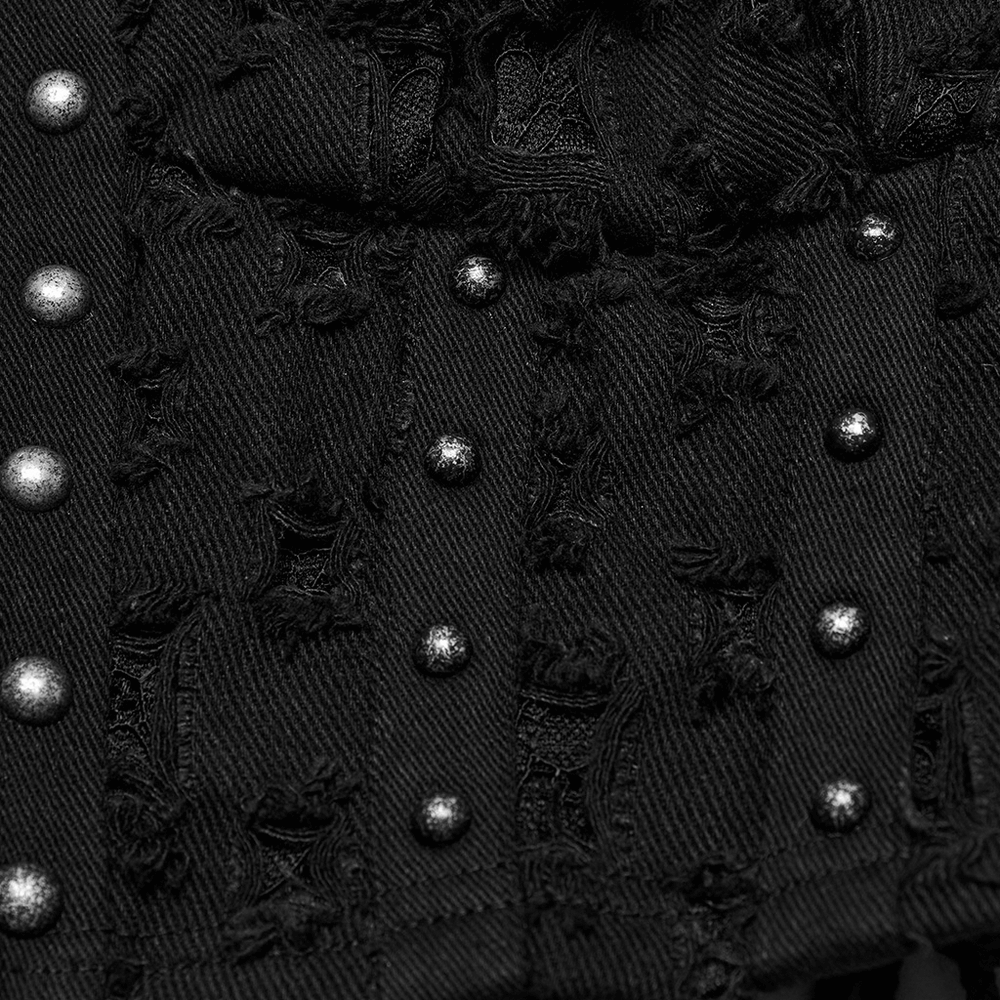 Close-up of a punk studded denim top featuring silver studs and distressed fabric texture.