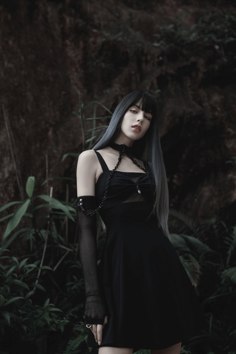 Model showcasing punk style elastic gauze choker and arm sleeves in a sleek black dress against a lush backdrop.