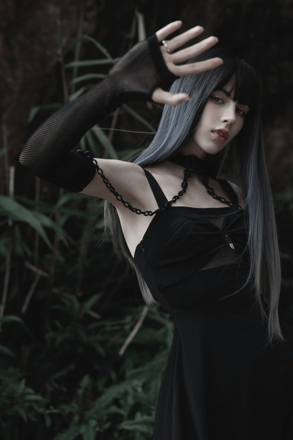 Model showcasing punk style elastic gauze choker and arm sleeves in a sleek black dress, set against lush greenery.