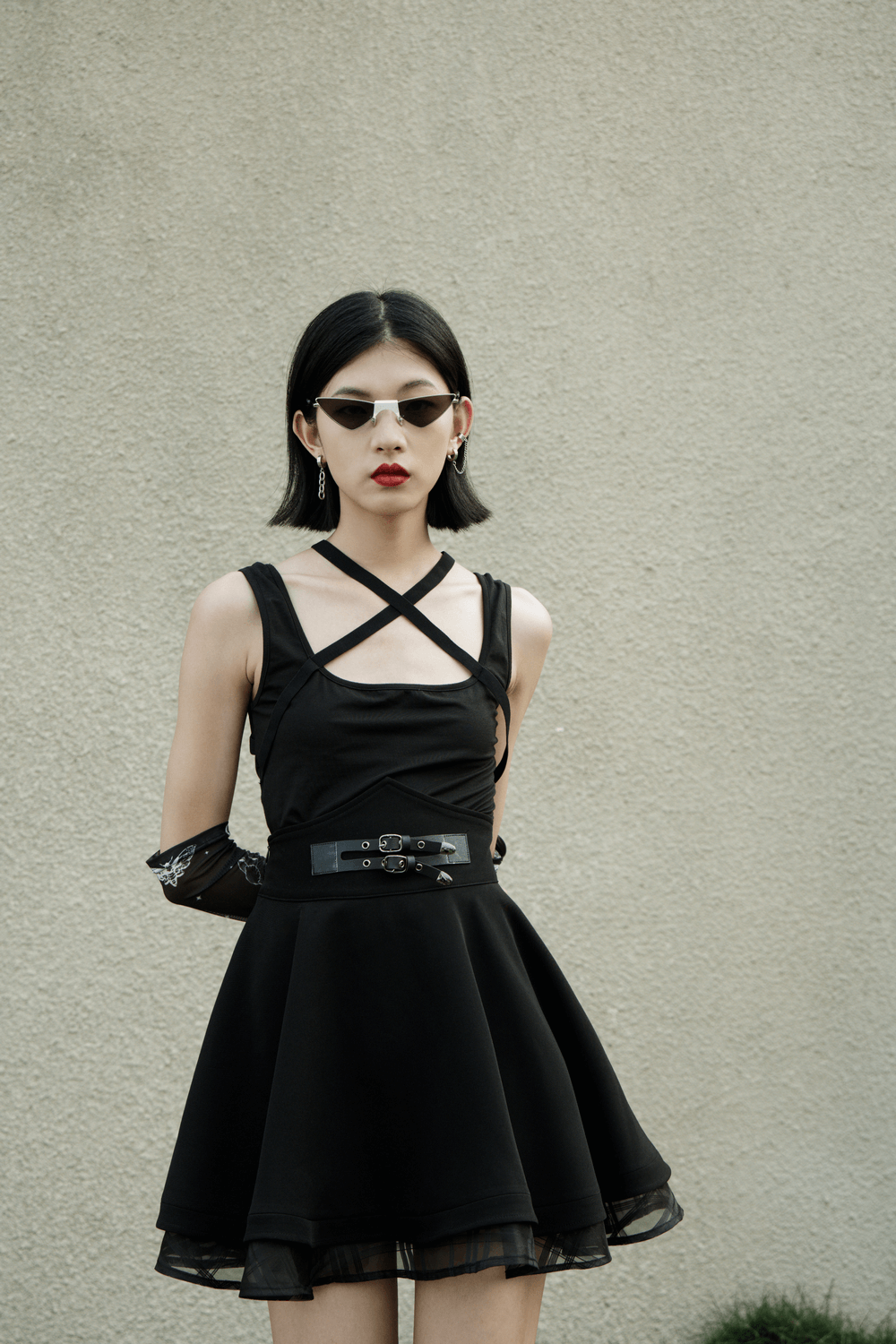 Stylish model in a black punk-style high waist layered skirt with buckle and sunglasses.
