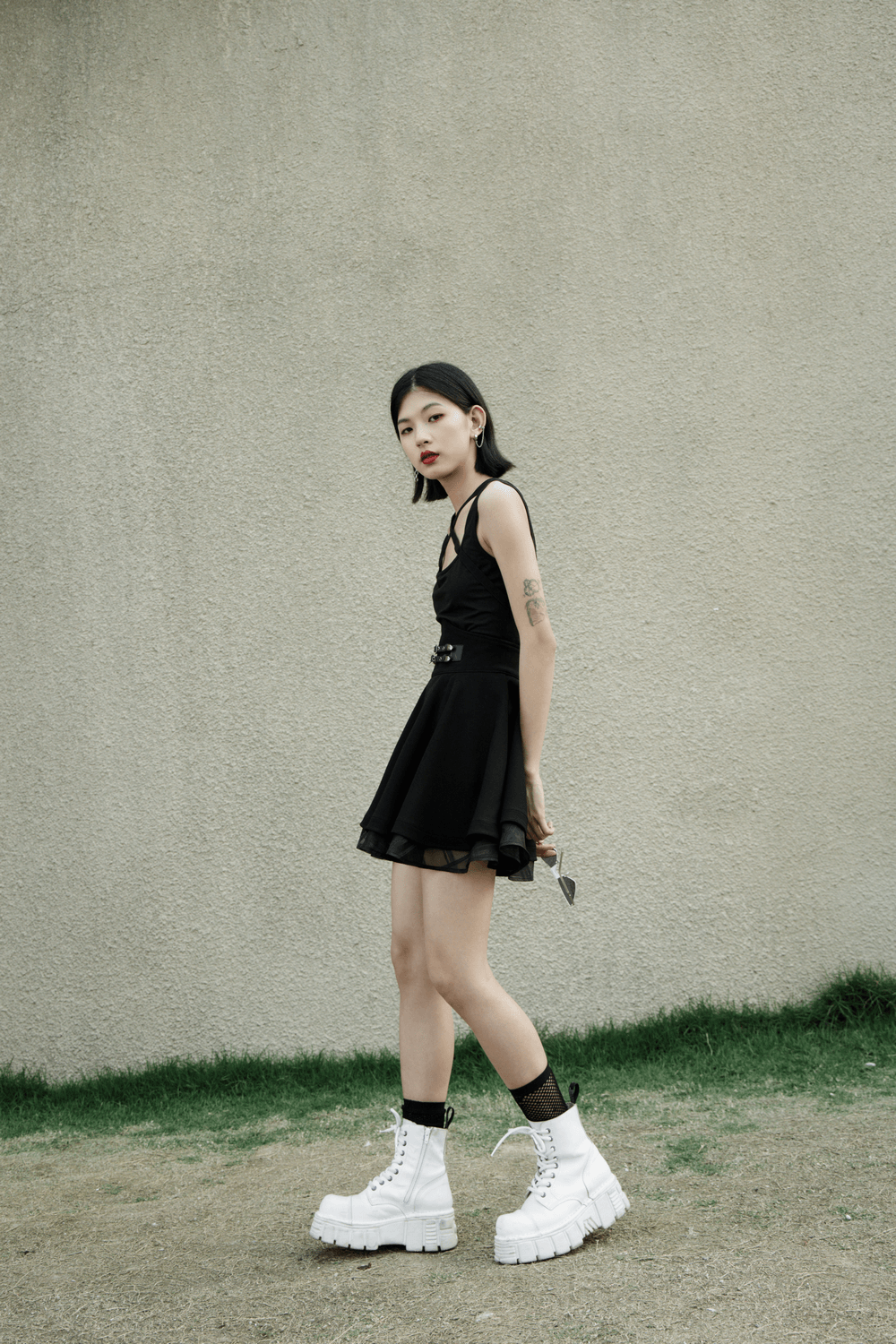 Model wearing a punk style high waist layered skirt with buckle and chunky white boots.