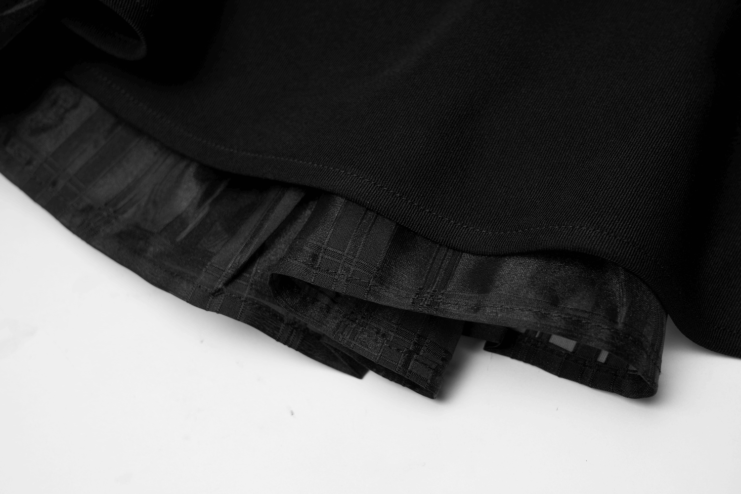 Close-up of a black layered skirt showcasing the twill top and checkered organza details.