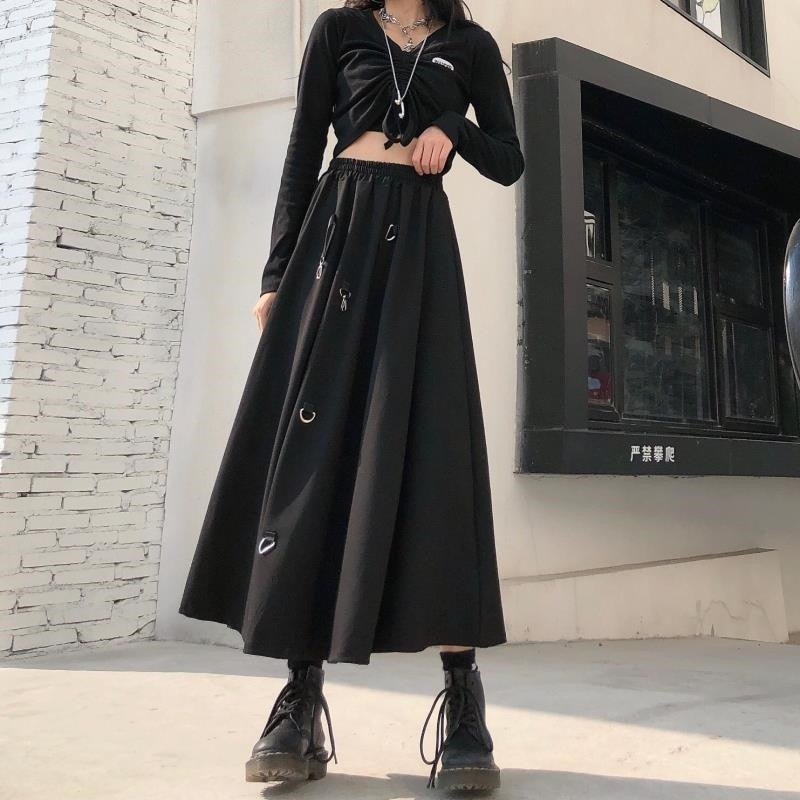 Punk style women's black irregular long skirt with buckles, paired with a trendy black top and stylish boots.