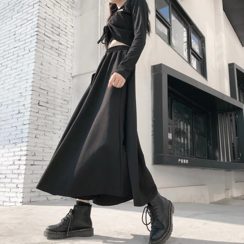 Fashionable woman in a long black punk skirt and boots, showcasing a stylish asymmetrical look.