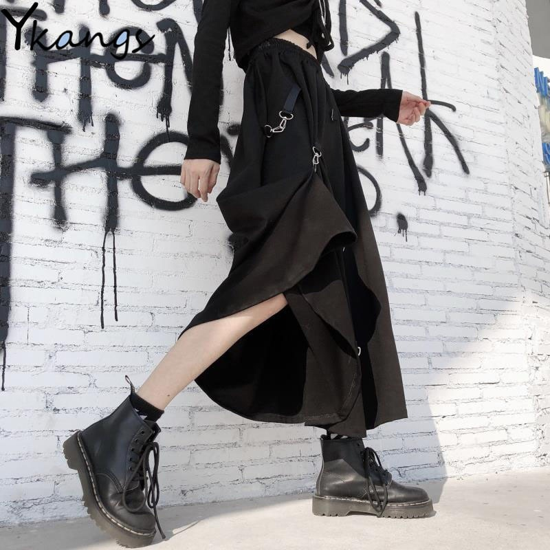 Punk style asymmetrical black skirt with buckles, paired with stylish combat boots against a graffiti wall.