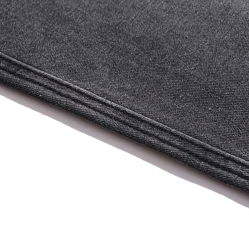 Close-up of black denim fabric showcasing texture and stitching detail.