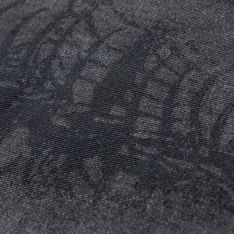 Close-up of skeleton print on punk style men's jeans fabric in dark color.