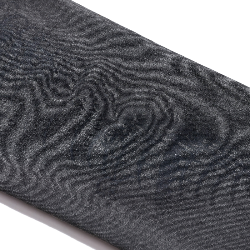 Close-up of bone print on punk style men's jeans fabric, showcasing unique skeleton design and dark color.