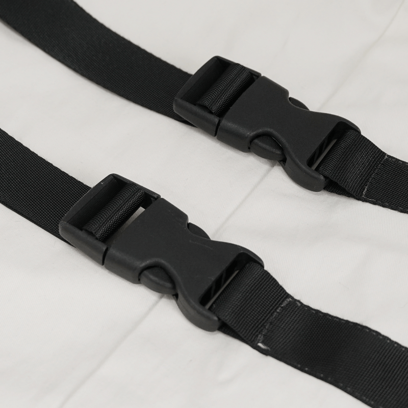 Close-up of black nylon straps and buckles featured on a punk style men's white long sleeve shirt.