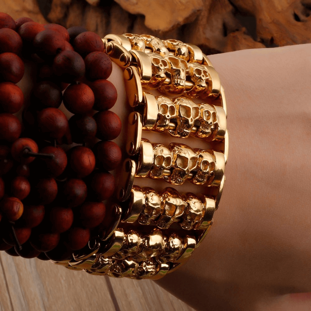 Stylish gold punk skull bracelet for men on wrist, showcasing multiple skull designs and trendy stainless steel fashion.