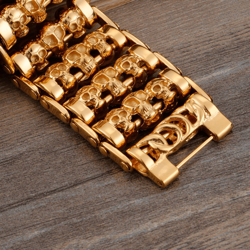 Men's punk style bracelet with gold skull charms on a wooden background. Trendy stainless steel accessory.