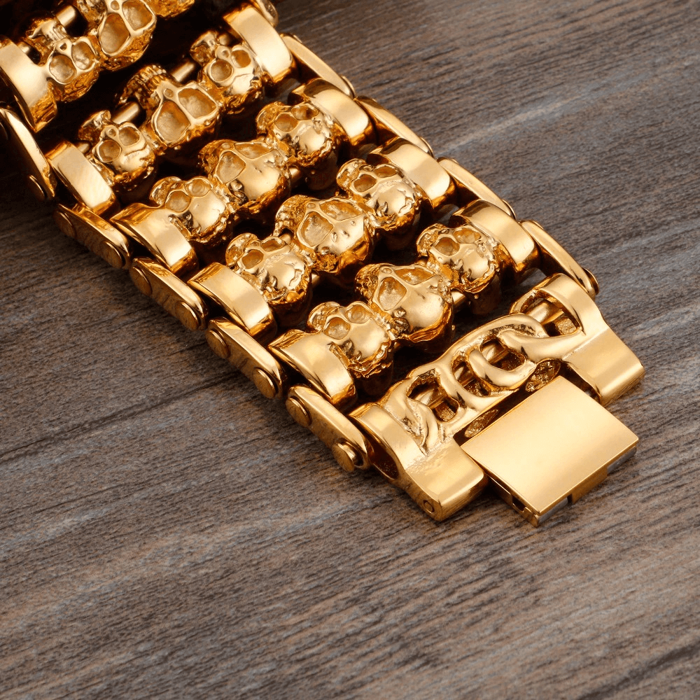 Close-up of a punk style gold skull charm bracelet for men, showcasing intricate skull designs and stainless steel links.