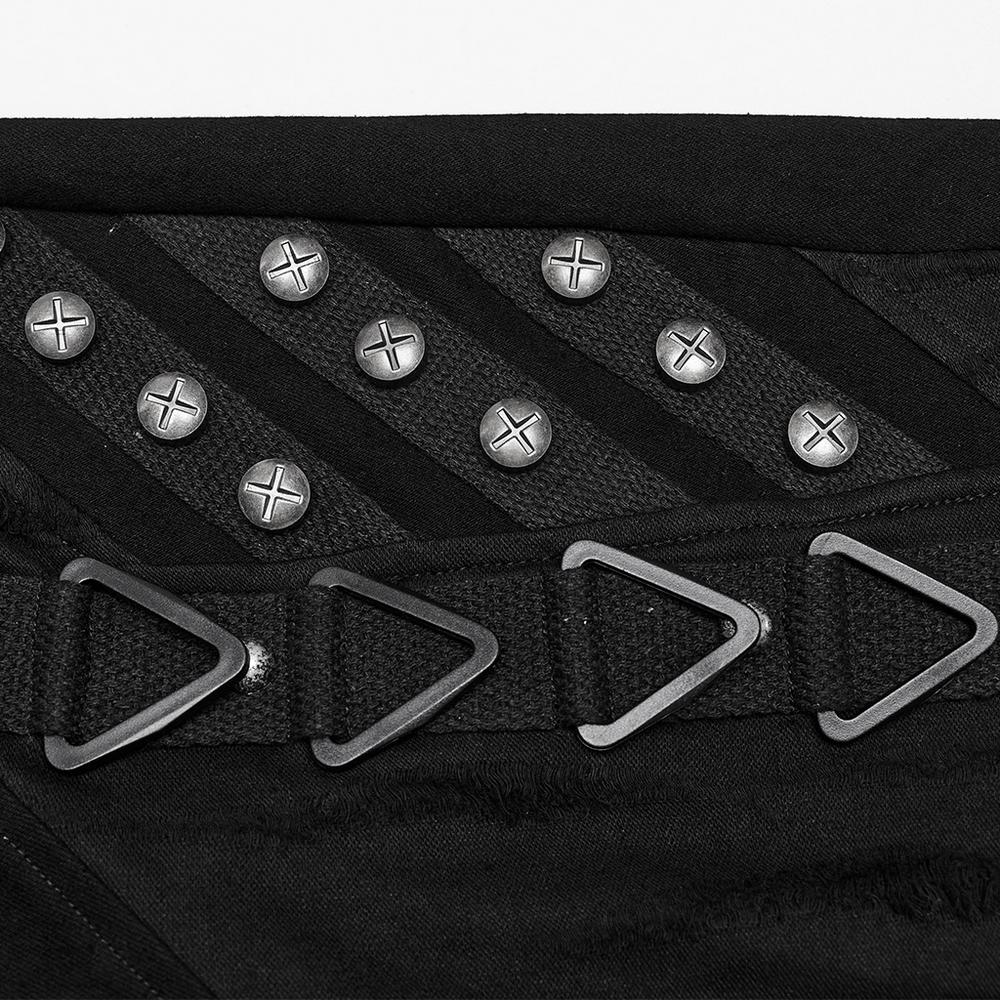 Close-up of punk style denim jeans featuring shiny rivets and triangular buckles for an edgy look.