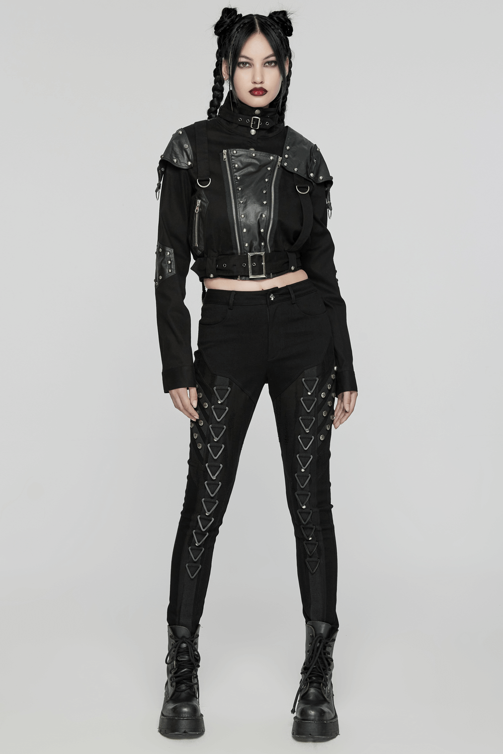 Edgy punk style model wearing a black leather jacket and spliced denim jeans with rivets.