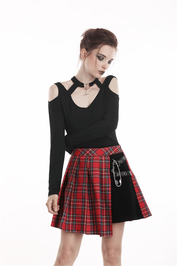 Stylish woman in black top and asymmetrical plaid mini skirt with safety pin detailing, perfect for punk rock vibes.
