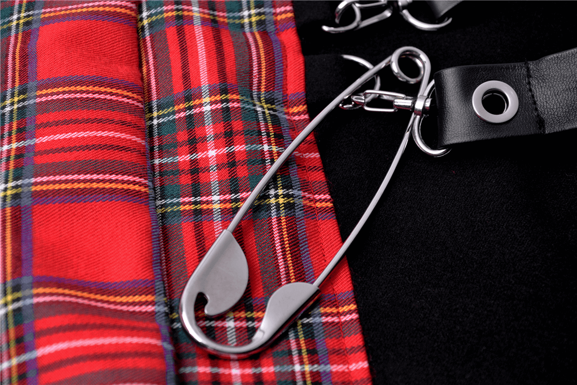 Close-up of edgy red and black plaid fabric with a safety pin detail, perfect for a punk rock mini skirt style.