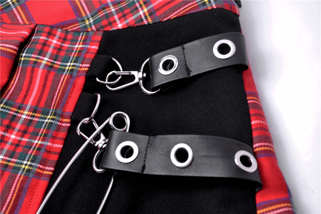 Close-up of edgy red and black plaid mini skirt with safety pin and leather detailing for a punk rock vibe.