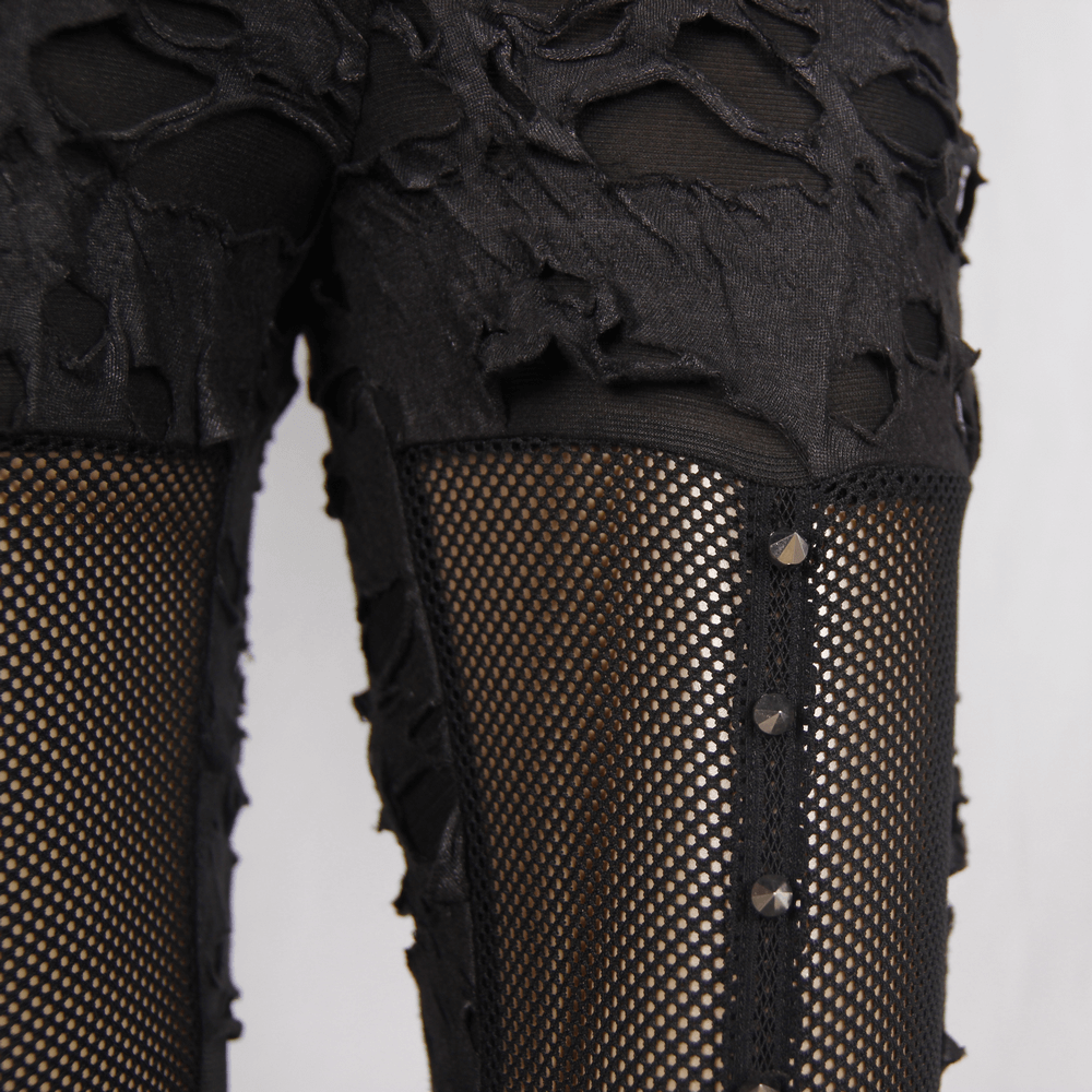 Close-up of black punk tattered leggings featuring torn inserts and mesh detailing, perfect for gothic fashion.