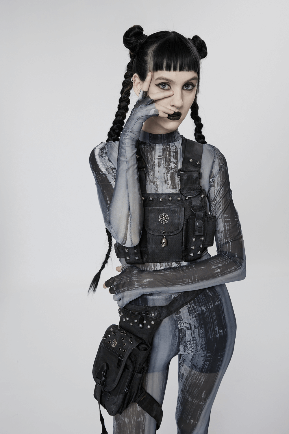 Punk techwear model in distressed mesh top and tactical harness, showcasing a post-apocalyptic aesthetic.