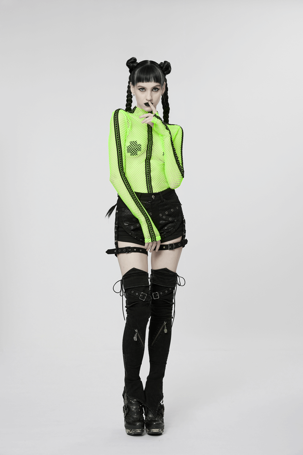 Model in neon mesh top and black shorts with thigh-high punk leg warmers, showcasing edgy fashion style.