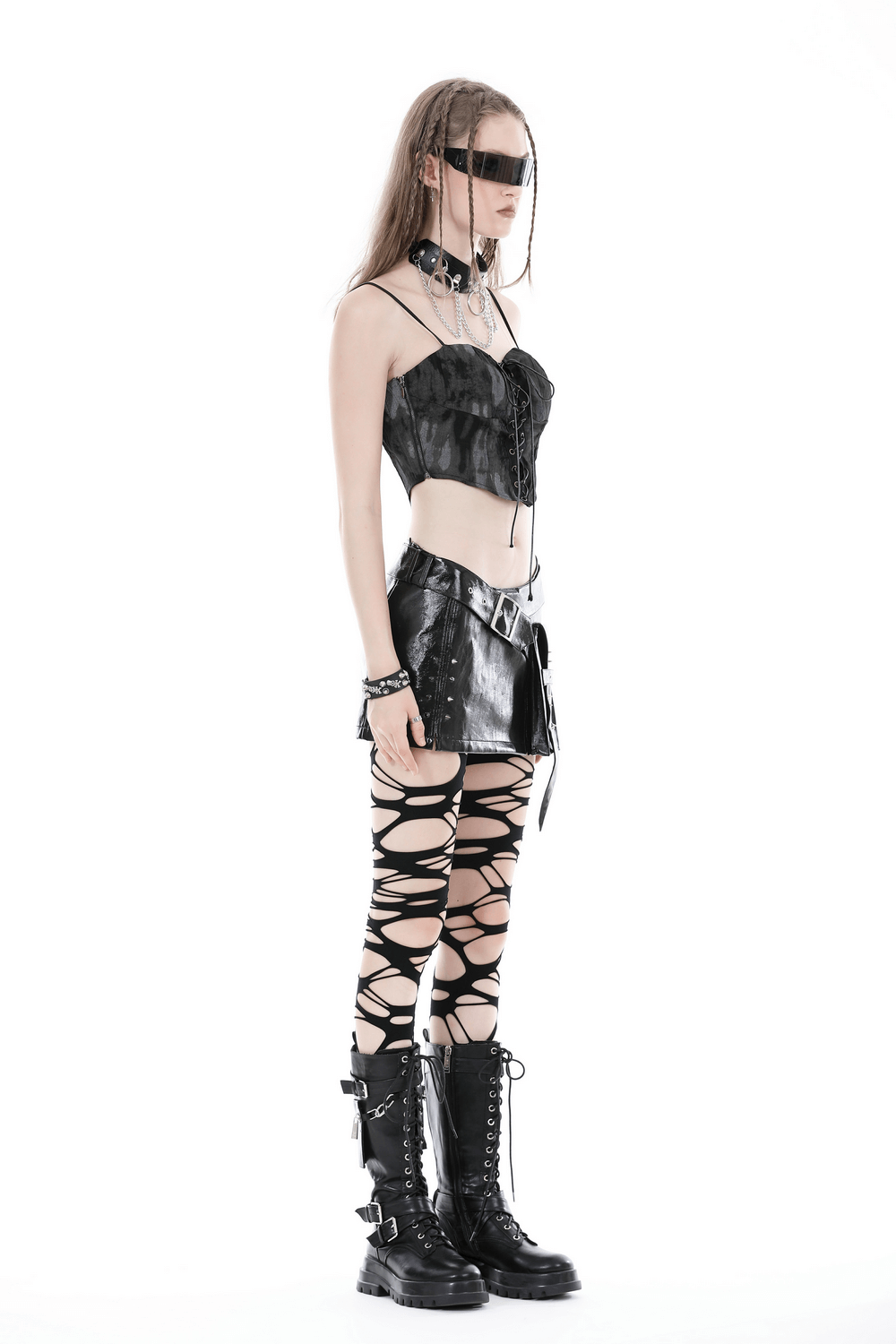Punk-style woman in a black mini skirt and lace-up leggings with combat boots, showcasing an edgy, gothic look.